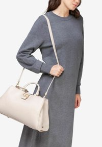 Lys beige læderhåndtaske med et struktureret design, guld hardware og dobbelte håndtag. Tasken har en lang skulderrem og en glat overflade.