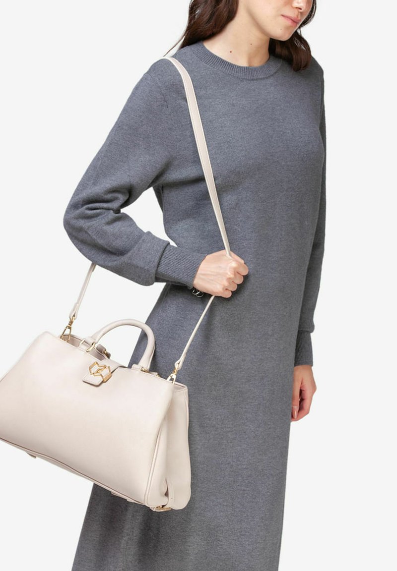 Lys beige læderhåndtaske med et struktureret design, guld hardware og dobbelte håndtag. Tasken har en lang skulderrem og en glat overflade.