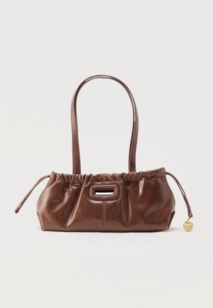 Brown leather handbag with gathered top, dual shoulder straps, rectangular cutout handle, and small gold heart charm on side.