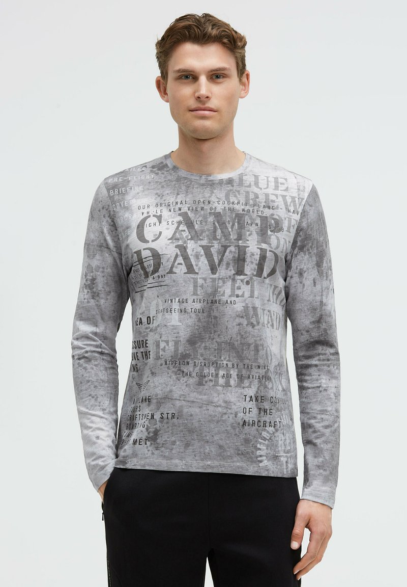 Langärmliges graues T-Shirt aus strukturiertem Stoff mit bedrucktem Text in verschiedenen Schriftarten und -größen, mit Rundhalsausschnitt und figurbetonter Passform.