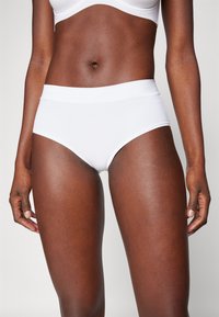 White cotton brief with a smooth texture, high waist design, and minimal stitching details, showcasing a fitted silhouette.