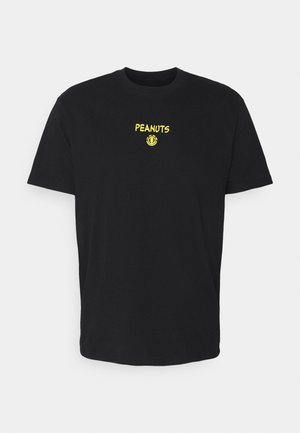 T-shirt noir à manches courtes avec petit texte jaune « PEANUTS » et logo circulaire centré sur le haut de la poitrine.