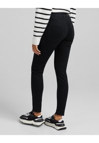 Svarta smala jeans i denim, med en midja i normal höjd, bakfickor och smal passform. Bärs tillsammans med svarta och vita sneakers.