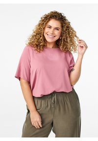 Krátký rukáv, volně střižený top z měkkého růžového materiálu; spárován s volnými kalhotami olivové zelené barvy s elastickým pasem a šňůrkou.