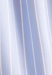 Tissu bleu clair avec de fines rayures blanches, présentant un motif de trame texturé. Surface lisse avec un léger éclat.