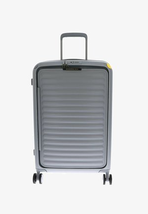 Valigia rigida grigia con texture a righe verticali, manico estraibile e accenti gialli. Presenta quattro ruote nere per la mobilità.