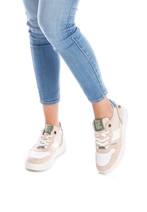 Zapatillas beige y blancas con un diseño de ante y malla. Presentan un acento verde en el talón, cordones blancos y perforaciones en la puntera.