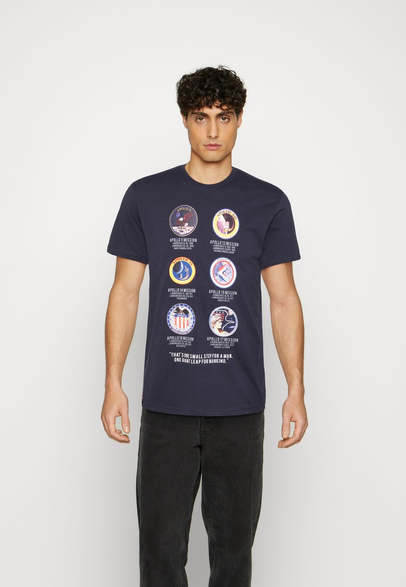 Navy-Baumwoll-T-Shirt mit sechs runden Apollo-Missionsgrafiken und einem Zitat am unteren Rand, auf einem schlichten Hintergrund.
