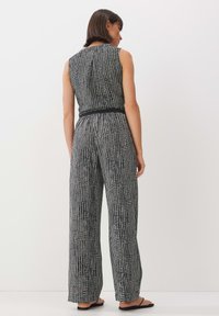 Black and white checked jumpsuit with a fitted top and wide-leg pants. Features a belted waist and sleeveless design.