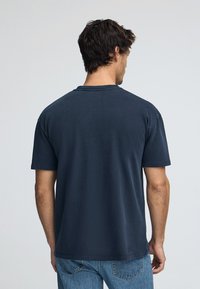 Marinblå bomullströja med kort ärm, rund halsringning och avslappnad passform. Slät textur, inga synliga mönster eller dekorationer.