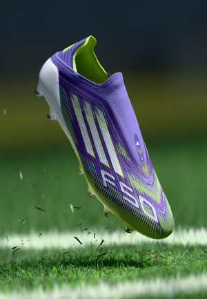 Purple and lime green soccer cleat with a textured upper, dynamic stripes, and a low-cut design. Features clear studs for traction on grass.