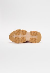 Suela de zapato de color beige claro, con patrones de agarre texturizados y punta redonda. Diseñada para tracción y estabilidad.