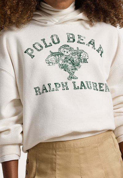Krémová mikina s modrým vintage grafickým obrazem medvěda v kostkovaném vzoru, s textem "POLO BEAR" a "RALPH LAUREN" v opotřebovaném písmu.