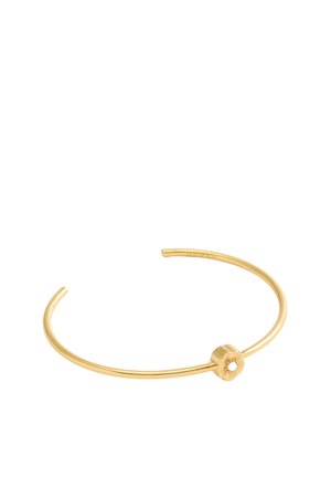 Bracelet en métal doré, au design minimaliste, avec un détail circulaire à l'avant, une finition lisse et des extrémités ouvertes.