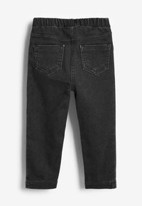 Pantalon en denim noir avec une taille élastique, deux poches arrière et un design de jambe fuselée. Texture douce et détails de couture minimaux.