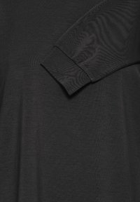 Haut noir à manches longues en tissu doux et lisse. Présente un design simple et décontracté avec une manche à revers et une texture subtile.