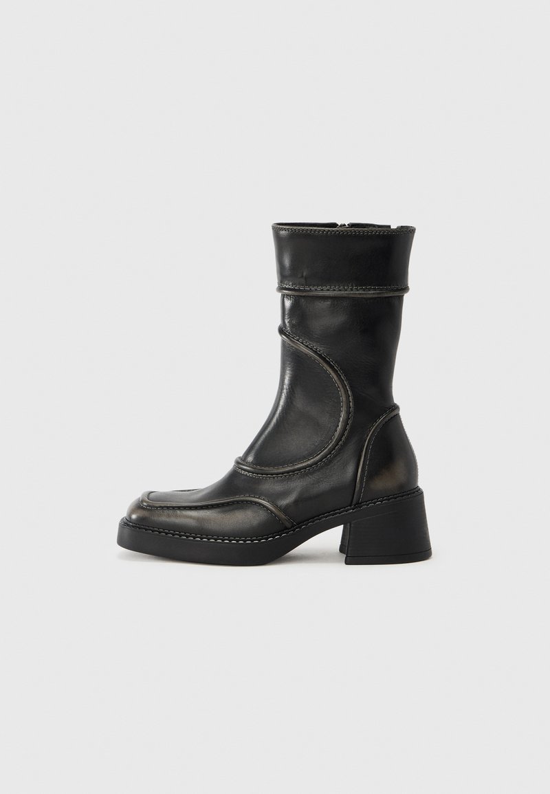 Μαύρο δερμάτινο μποτάκι αστραγάλου με στρογγυλε μένη μύτη, λεπτομέρειες με υφή, ραφές και χοντρό τακούνι. Κλείσιμο με φερμουάρ στο πλάι και λεία επιφάνεια.