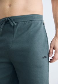 Grønne teksturerte shorts med justerbar livlinje, har sidelommer og en subtil svart "BOSS" logo på låret.