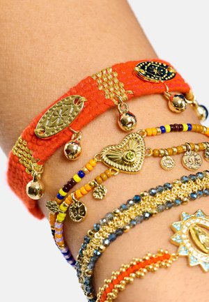 Ensemble de bracelets colorés comprenant une bande tissée orange avec des accents dorés, des rangs de perles jaunes, bleues et marron, ainsi que des breloques décoratives.