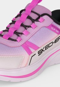 Gros plan d'une chaussure Skechers slip-ins rose et violette avec des lacets élastiques noirs et une semelle blanche avec des accents roses.