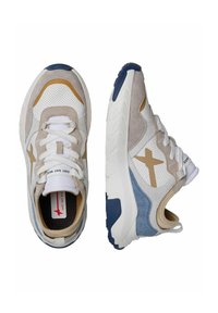 Sneaker con una combinazione di rete bianca, suede beige e dettagli blu navy. Suola spessa con battistrada testurizzato e sistema di allacciatura prominente. Dettaglio del logo dorato.
