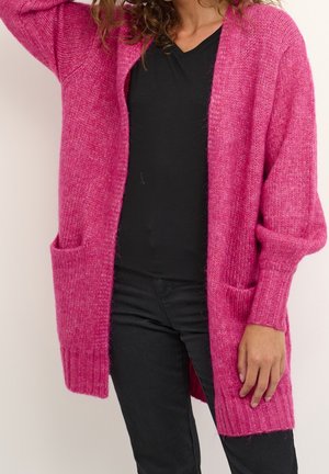 Cardigan flou rose avec des manches longues et deux poches avant, présentant une texture côtelée et un design ouvert.