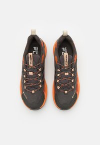 Czarne i pomarańczowe buty do biegania z siateczkowym wierzchem, odblaskowymi akcentami i teksturowanymi gumowymi podeszwami; posiadają system sznurowania oraz logo GORE-TEX.