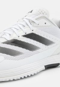 Witte sportschoen met een mesh bovenzijde, zwarte gestreepte accenten en een gestructureerde rubberen zool. Inclusief witte veters en een gevoerde kraag.