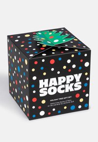 Svart presentlåda med färgglada prickar, grön trädformad detalj på toppen, med "HAPPY SOCKS"-logotyp och julinspirerad design.