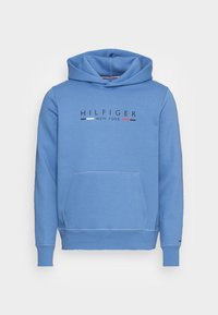 Felpa leggera azzurra con cappuccio regolabile, tasca frontale e testo "HILFIGER NEW YORK" in nero, bianco e rosso. Tessuto in cotone morbido.
