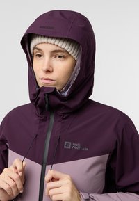 Giacca impermeabile viola con colletto alto, cappuccio con cordino e dettagli in viola chiaro. Presenta una zip frontale e dettagli con logo.