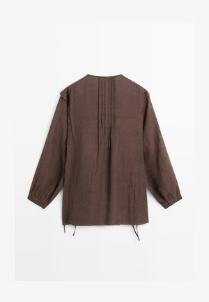 Brązowa bluzka z długim rękawem, plisami na plecach, mankietami na guziki i luźnym krojem, leżąca płasko na białym tle.