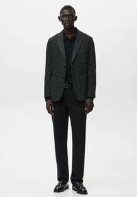 Dunkelgrauer Wollblazer mit Kerbkragen, schwarzer Knopfverschluss, kombiniert mit einem schwarzen Hemd und dunklen Hosen. Schwarze Lederschuhe vervollständigen den Look.