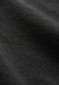 Musta kangas, jossa on pehmeä tekstuuri ja hillitty, tasainen kuvio. Materiaali vaikuttaa kevyeltä ja hieman heijastavalta.