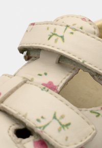 Λευκά σανδάλια με φλοράλ σχέδιο και ροζ και πράσινες λεπτομέρειες, με δύο ρυθμιζόμενους ιμάντες και υφή στις άκρες για ασφαλή εφαρμογή.