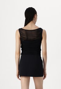 Rochie neagră cu un corset semi-transparent, plisat și fustă ajustată. Design fără mâneci, cu decolteu rotund și textură de țesătură netedă.