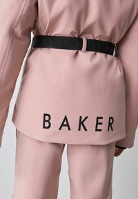 Rozā ūdensizturīga jaka ar melnu elastīgu jostu, kurā atkārtoti redzams teksts "BAKER". Gluda tekstūra un pielāgots piegriezums ar minimālu dizainu.