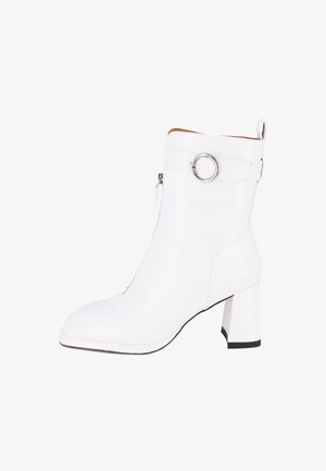 Stivale bianco alla caviglia realizzato in materiale sintetico liscio, con punta quadrata, tacco a blocco, chiusura con zip e un accent decorativo in argento a forma di anello.