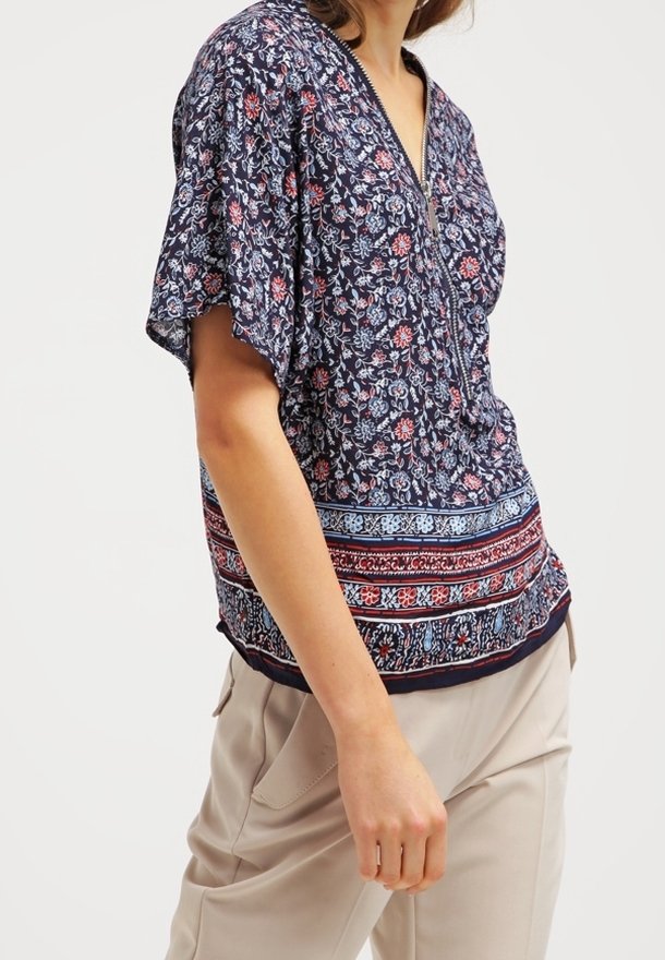 Laivastonsininen kukkakuosiset pusero lyhythihaisilla, V-kaula-aukolla ja värikkäällä reunapaneelilla; kevyt kangas, jossa on pehmeä ja teksturoitu pinta.