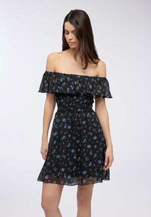 Abito nero off-the-shoulder con motivi floreali in blu e verde, vita arricciata e dettagli a strati di volant sul colletto.