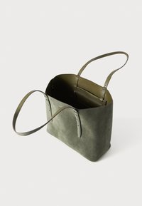 Sac fourre-tout en daim vert olive avec deux poignées, forme rectangulaire et une poche intérieure zippée pour l'organisation. Texture lisse.