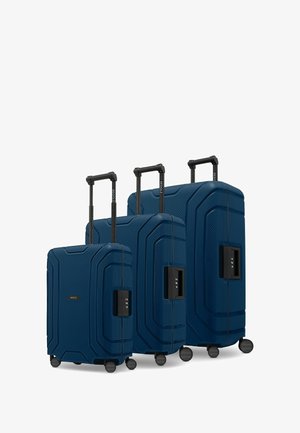 Tre valigie blu navy di diverse dimensioni, con modelli testurizzati, gusci rigidi, manici telescopici e quattro ruote ciascuna.
