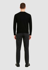 Black sweater with a classic fit, featuring a round neckline, paired with dark gray tapered pants and black shoes. Smooth texture.