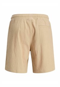 Beige rövidnadrág texturált anyagból, rugalmas derékkal és hátsó zsebbel. Egyszerű dizájn, nincs látható minta vagy díszítés.