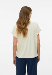 Lys beige afslappet-top med korte ærmer og en blød tekstur. Har en rund kant og ingen synlige lukninger.
