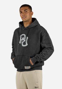 Gray hoodie made of cotton, featuring a front kangaroo pocket and a distinct logo design. Thick drawstrings and ribbed cuffs complete the look.