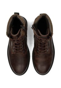 Un par de botas de cuero marrón con cordones hasta el tobillo, con cuellos acolchados y cremalleras laterales, vistas desde arriba sobre un fondo blanco.