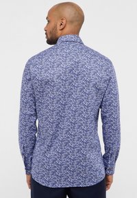 Camicia a maniche lunghe blu con motivo floreale bianco, dotata di colletto classico e polsini con bottoni, realizzata in tessuto leggero.