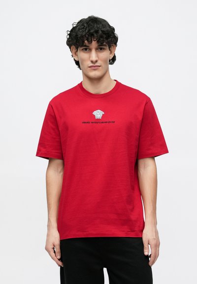 Κόκκινο βαμβακερό t-shirt με στρογγυλή λαιμόκοψη και κοντά μανίκια, με λευκό γραφικό λογότυπο στο στήθος. Λεία υφή, άνετη εφαρμογή.