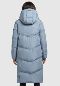 Giacca puffer azzurro chiaro con cappuccio, caratterizzata da un'imbottitura a zig-zag, maniche lunghe e un logo sull'orlo inferiore. Materiale morbido e resistente all'acqua.